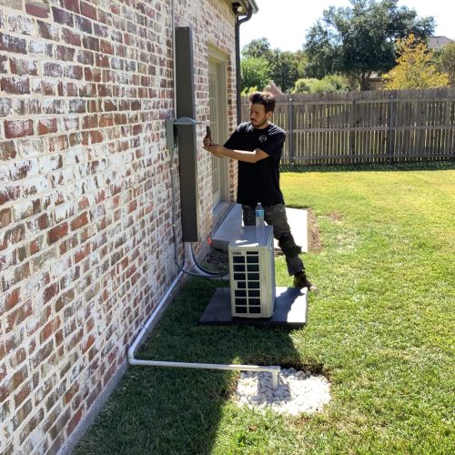 A worker tuning up an ac unit in preparation for warmer months